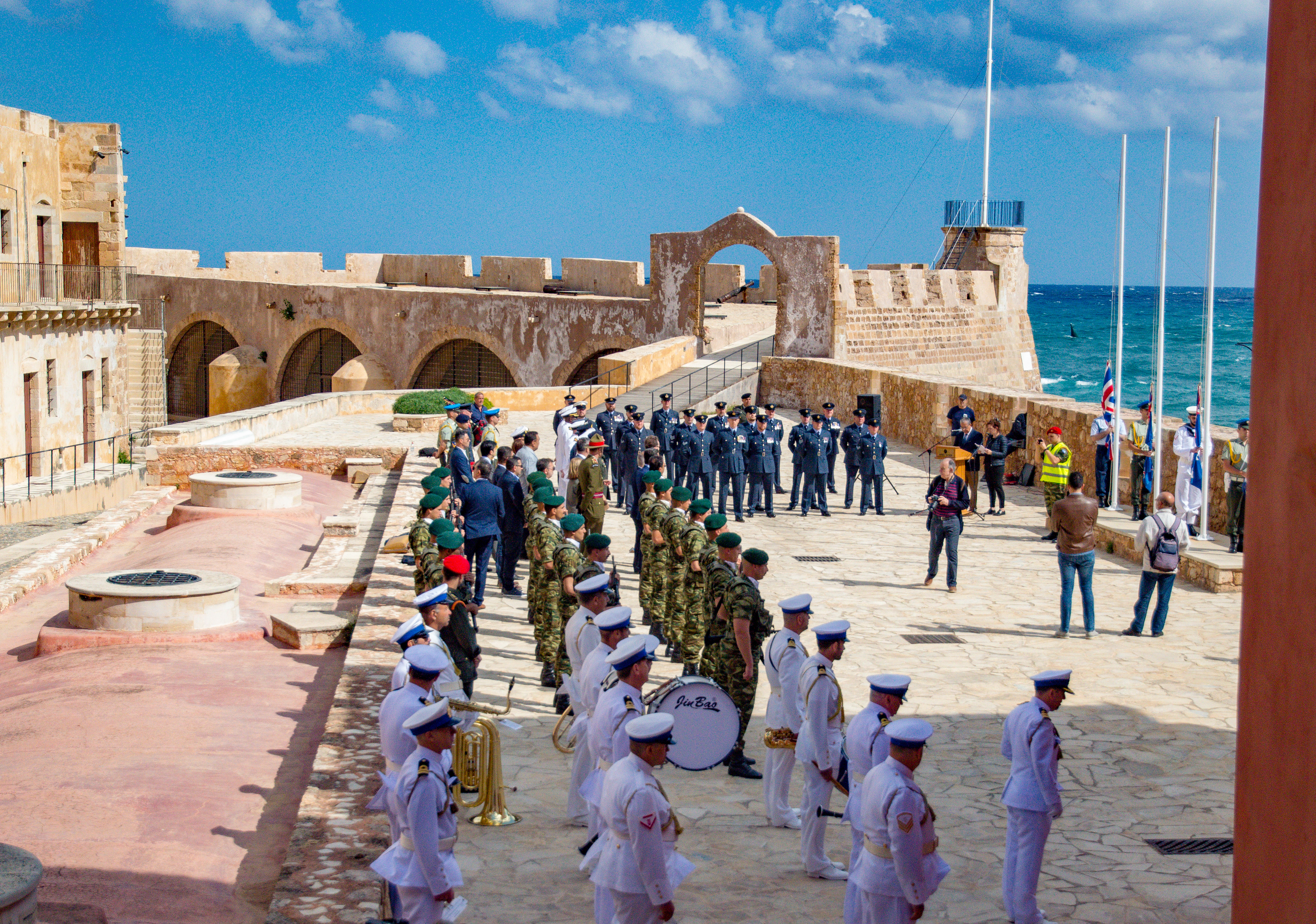 Personnel and Royal Navy band stand by coast side in parade.